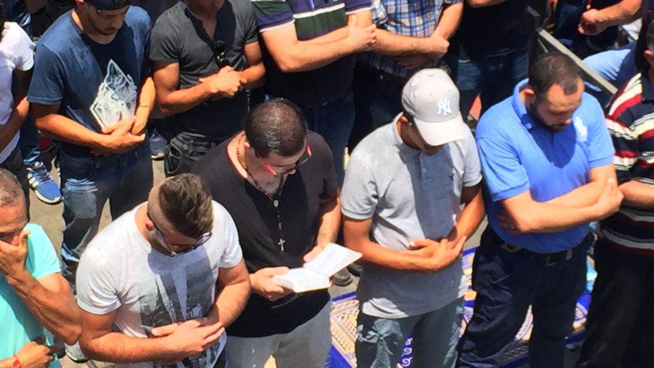 Nidal Aboud, a Christian, holds a Bible and prays beside Muslims in Jerusalem, where there recently have been clashes between Israeli forces and Palestinians.