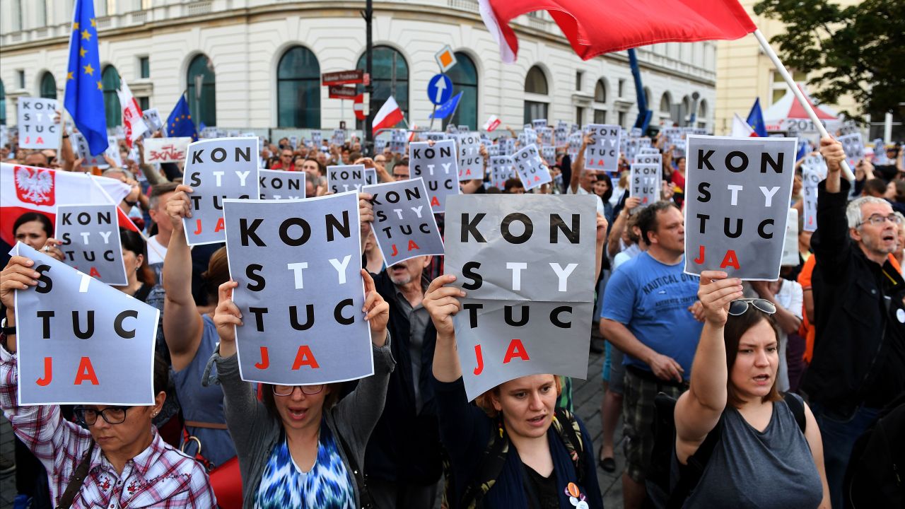 Protesters hold posters reading "constitution" during a protest in front of the Presidential Palace in Warsaw.
