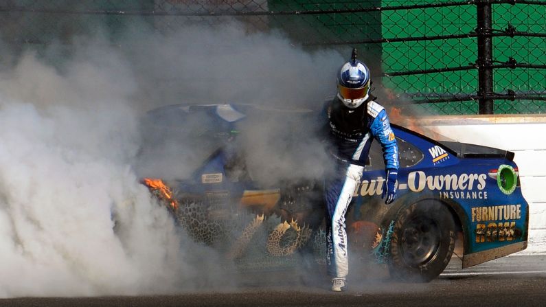 Martin Truex Jr. climbs out of his car after crashing with Kyle Busch at the Brickyard 400 on Sunday, July 23. Despite not finishing the race, Truex still leads the standings in NASCAR's top circuit.