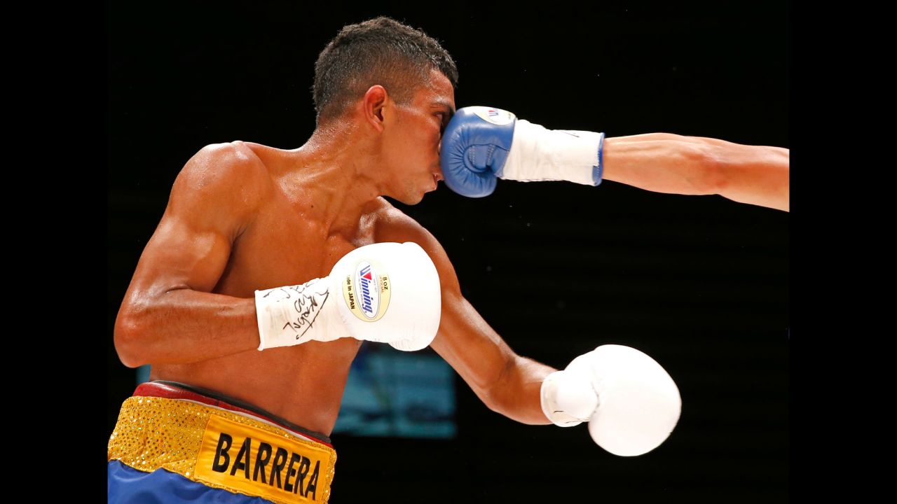 Robert Barrera eats a punch from Ryoichi Taguchi during their light-flyweight bout in Tokyo on Sunday, July 23. Taguchi defended his WBA title with a ninth-round stoppage.