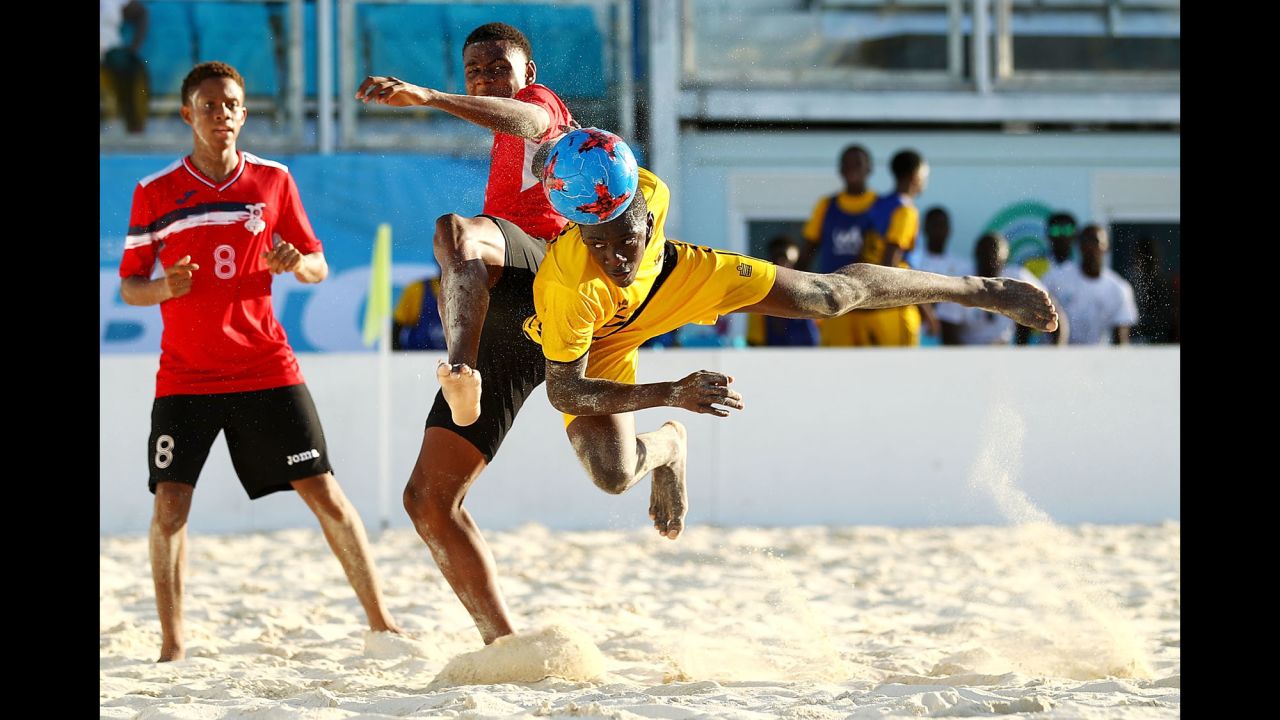 Jajuan Williams, right, heads a ball for Antigua and Barbuda during a beach soccer match at the Youth Commonwealth Games on Wednesday, July 19. Trinidad and Tobago won after a penalty shootout.