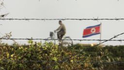 DANDONG, LIAONING, CHINA - OCTOBER 18:  A North Korean man riding a bicycle near a North Korean flag is seen through the newly installed fence by the Chinese side in this picture taken on October 18, 2006 in the Chinese border city of Dandong, Liaoning Province of China. China urged North Korea not to escalate international tensions, after Pyongyang said the UN resolution imposing sanctions over its nuclear weapons test was a "declaration of war."  (Photo by Cancan Chu/Getty Images)