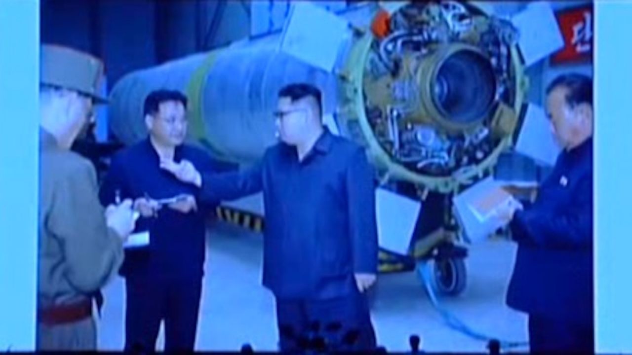 North Korean leader Kim Jong Un standing in front of the Hwasong-10, with the engine visible.