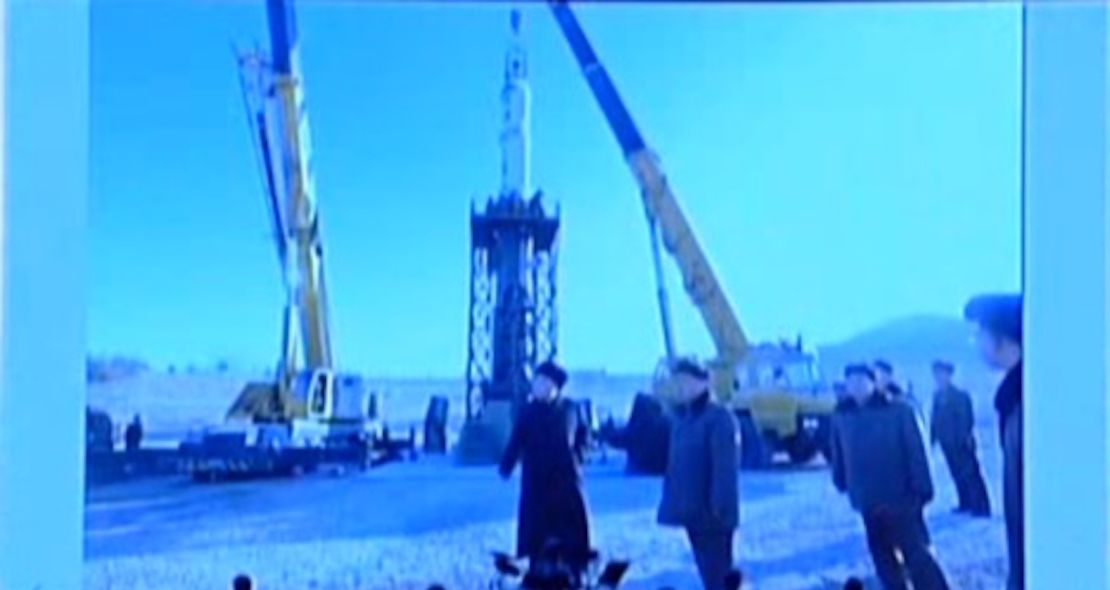 Kim Jong Un stands near a missile being loaded onto a test stand.