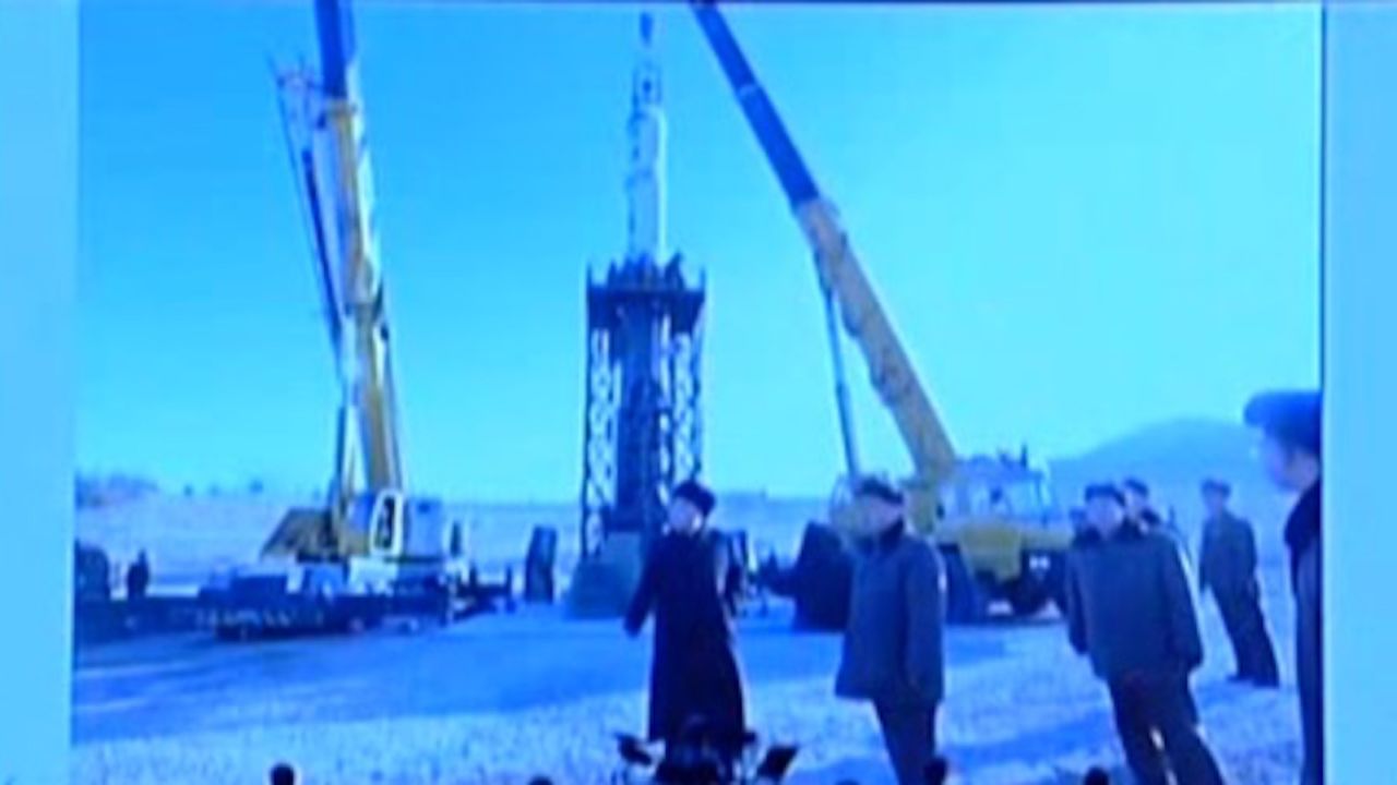 Kim Jong Un stands near a missile being loaded onto a test stand.
