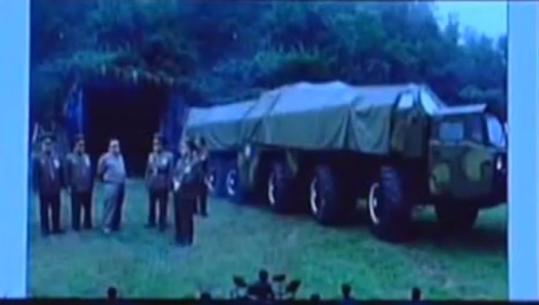 Kim Jong Il next to a transporter erector launcher (TEL) in front of what might be a missle storage site.