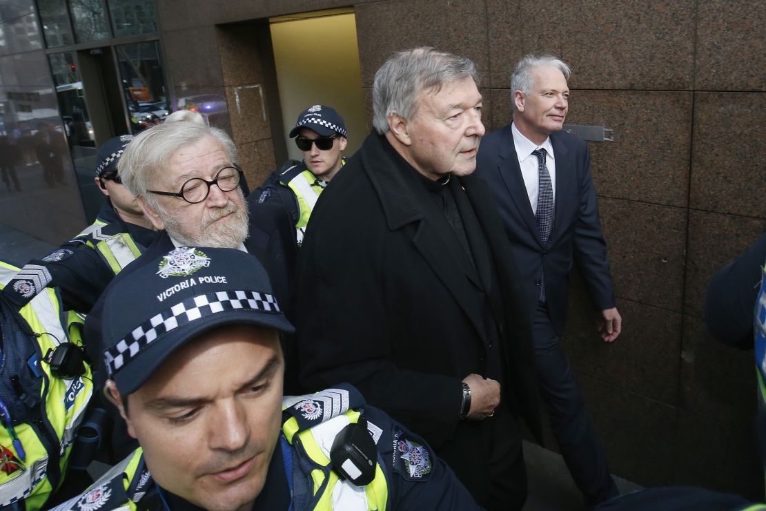 Cardinal Pell (C) walks with a heavy police guard from his barristers Robert Richter office to the Melbourne Magistrates' Court on July 26.