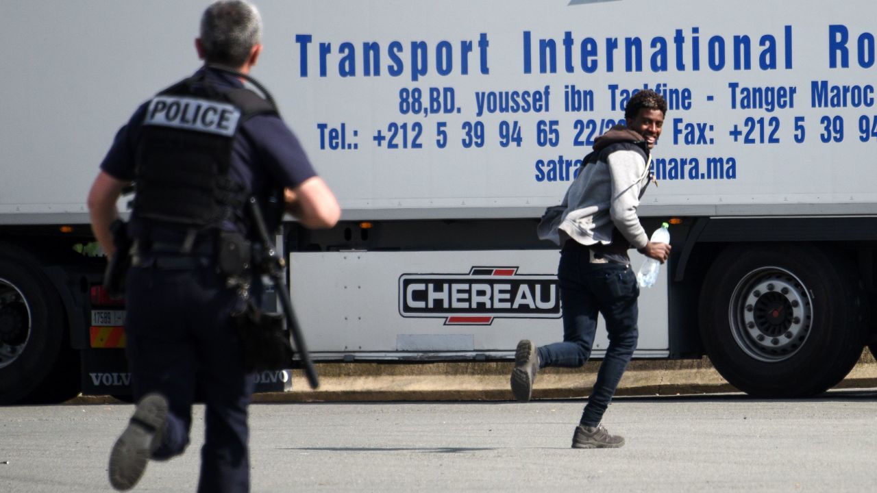 A police officer chases a youth suspected of being a migrant in a lorry park on the outskirts of Calais.