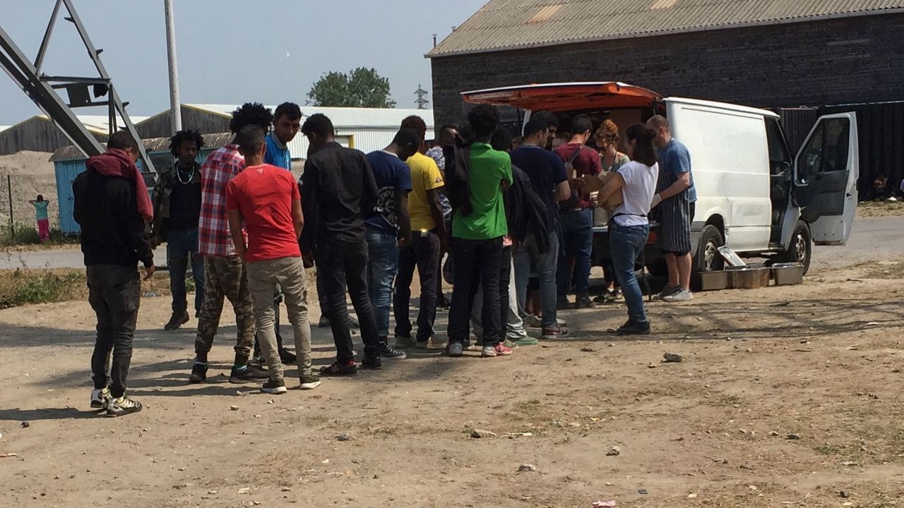 Migrants queue to receive food distributed by an NGO on an industrial estate in Calais. 