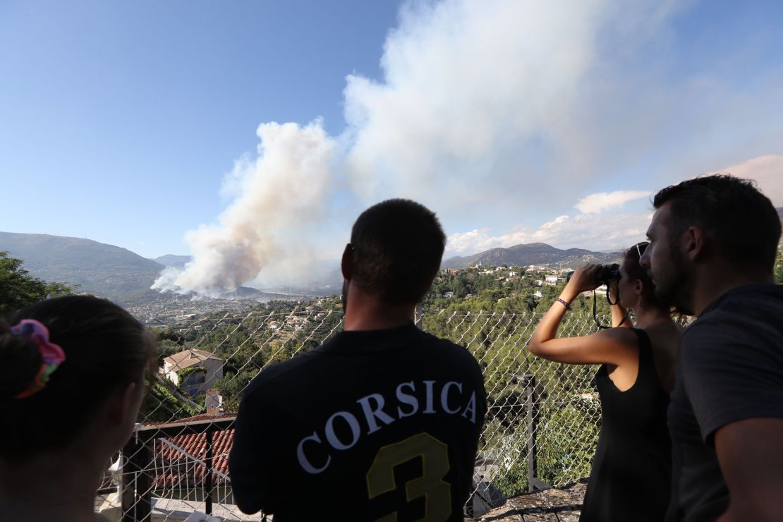 People watch smoke billow over Carros, southeastern France.