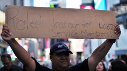 A protester displays a placard during a demonstration against US President Donald Trump, in front of the US Army career center in Times Square, New York, on July 26, 2017. 
Trump announced on July 26 that transgender people may not serve "in any capacity" in the US military, citing the "tremendous medical costs and disruption" their presence would cause. / AFP PHOTO / Jewel SAMAD        