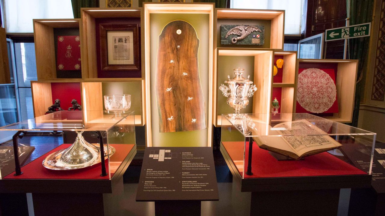 The Royal Gifts exhibition is arranged geographically, with objects from the same continent displayed in the same room. The Europe section features a large wooden artwork from Slovakia (center), a silver samovar from Russia (center-right) and Icelandic manuscripts given to the Queen by President Ásgeir Ásgeirsson in 1963 (upper-left, with red cover).