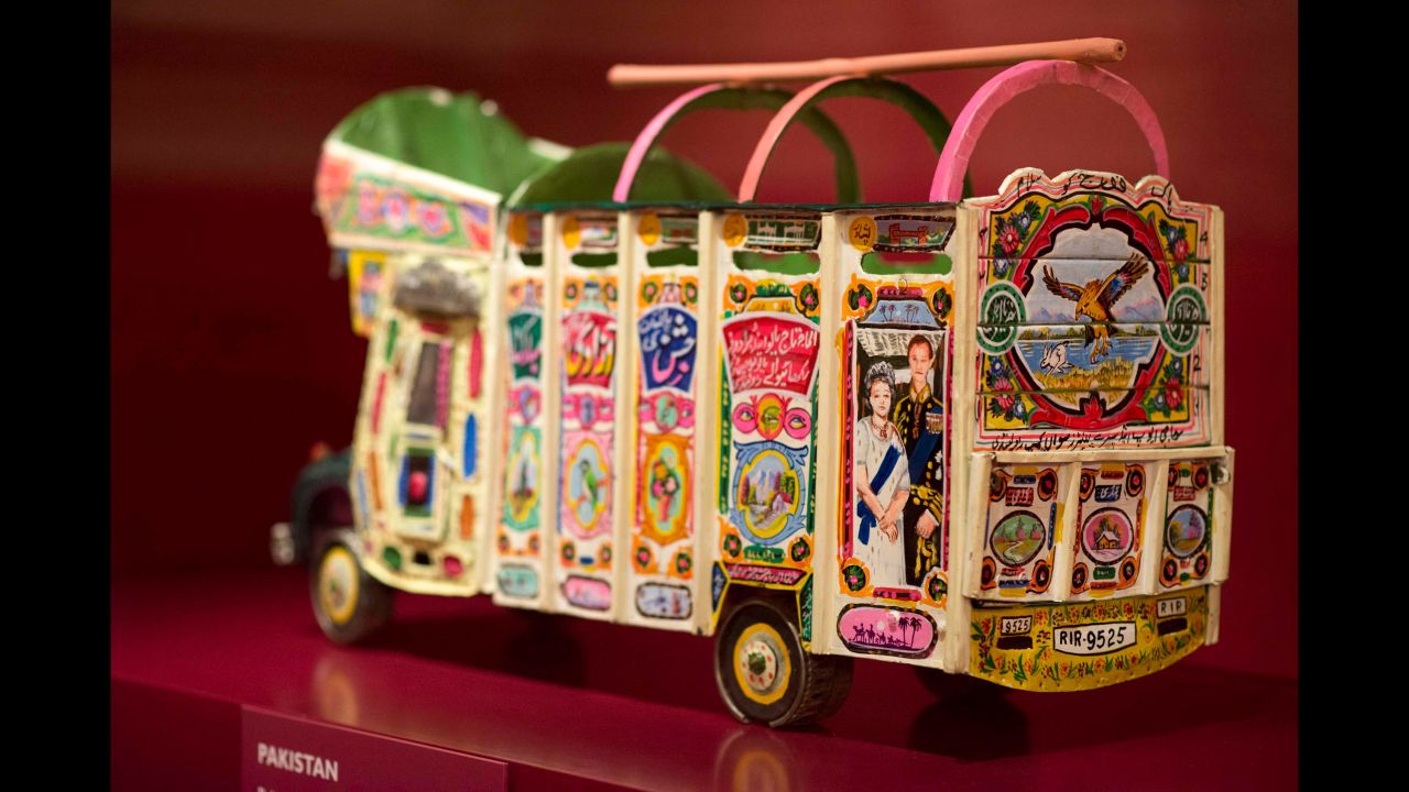 An association of Pakistani drivers presented this brightly colored tin model bus to the Queen and Prince Philip in 1997. It includes a picture of them and the flags of the UK and Pakistan.