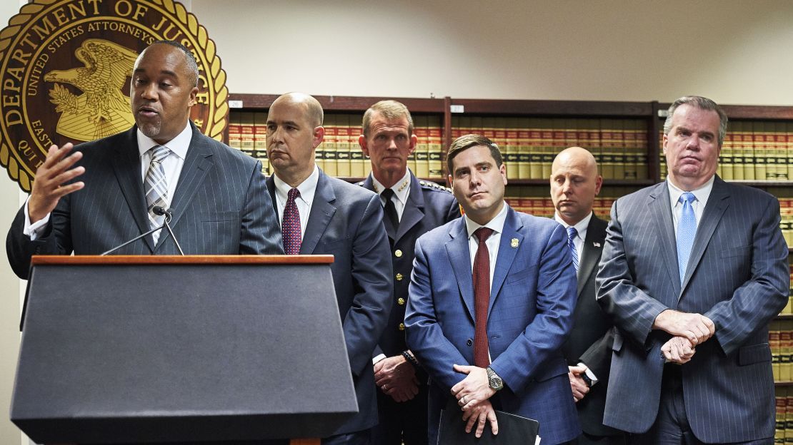US Attorney Robert Capers, left, flanked by members of the FBI and Nassau and Suffolk County Police, speaks at a news conference in March. They announced the indictment of suspects in seven gang-related slayings.