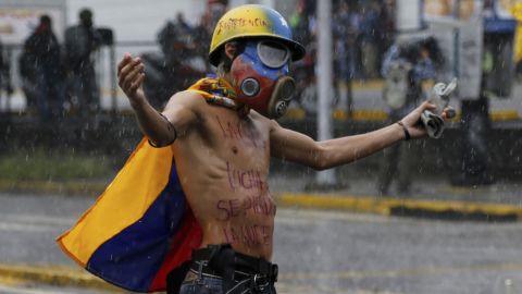 A protester faces off against national guard troops as clashes continued Friday in Caracas despite rain.