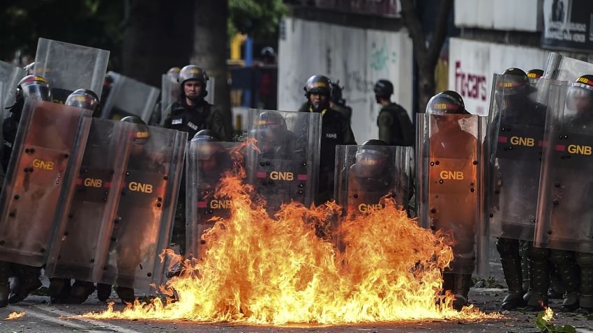 Members of the National Guard use their shields behind a fire during clashes with anti-government demonstrators in Caracas, on July 26, 2017. Venezuelans blocked off deserted streets Wednesday as a 48-hour opposition-led general strike aimed at thwarting embattled President Nicolas Maduro's controversial plans to rewrite the country's constitution got underway. /