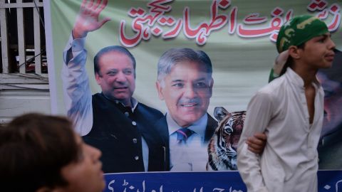 Supporters of ousted Pakistani prime minister Nawaz Sharif stand next to a banner featuring images of Sharif (L) and his brother Shahbaz Sharif (C) on July 29.