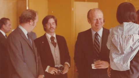 President Gerald Ford, right, visited the US Beijing Liaison Office in 1976. Booth, seen here holding a camera, was responsible for assisting the Secret Service with Ford's security on the ground. "My role was guaranteeing that no one came into his immediate area uninvited," Booth remarked. Booth's lapel pin acted as a secret signal to his fellow Secret Service special agents and White House staff that he was armed. "I probably have my Smith and Wesson  Model 19 .357 magnum attached to my belt," he explained. 