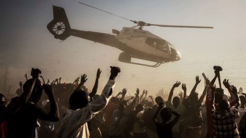 Supporters of Kenyan presidential candidate Raila Odinga wave as he departs in a helicopter after addressing a rally in Kisumu on August 3.