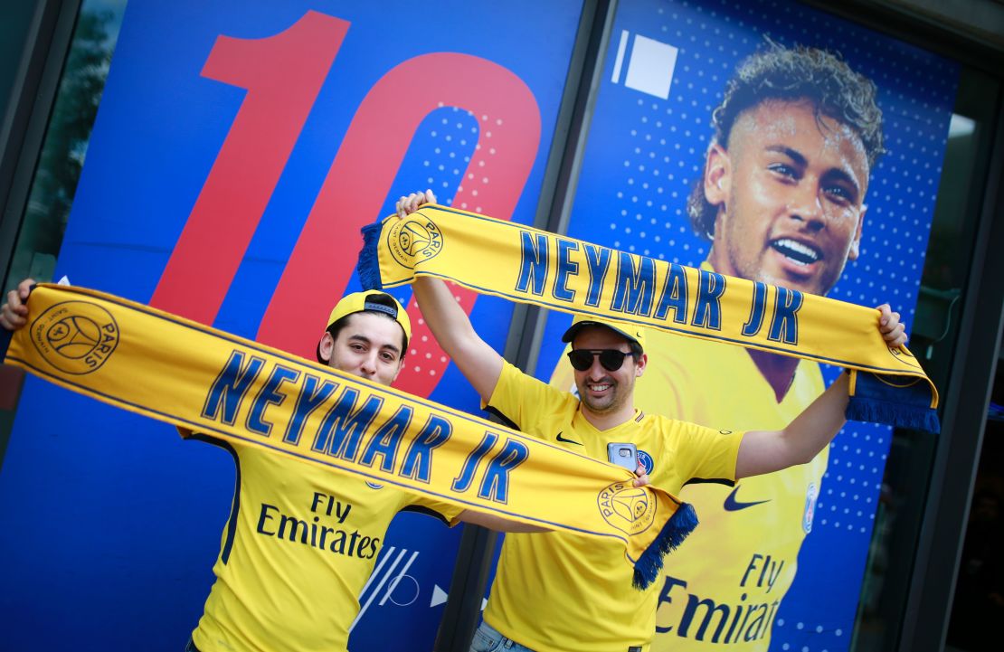 Supporters of Paris-Saint-Germain's new signing Neymar pose with scarves outside the Paris-Saint-Germain (PSG) football club store on the Champs Elysees avenue in Paris on August 4