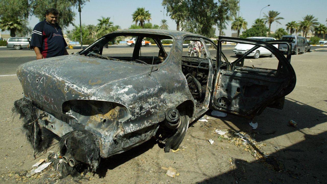 An Iraqi looks 24 September 2007, at a burnt car on the site where Blackwater guards who were escorting US embassy officials opened fire in the western Baghdad neighbourhood of Yarmukh,  a shootout which left, 16 September 2007,  nine civilians and a policeman dead. Iraq said today that it will await the outcome of an investigation into the killing of 10 people during the shootout before taking any action against the company. AFP PHOTO/ALI YUSSEF (Photo credit should read ALI YUSSEF/AFP/Getty Images)