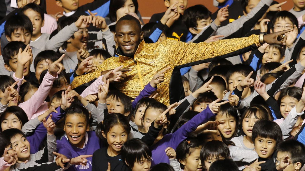 Bolt and children do his signature pose during a track clinic in Tokyo in 2013. 