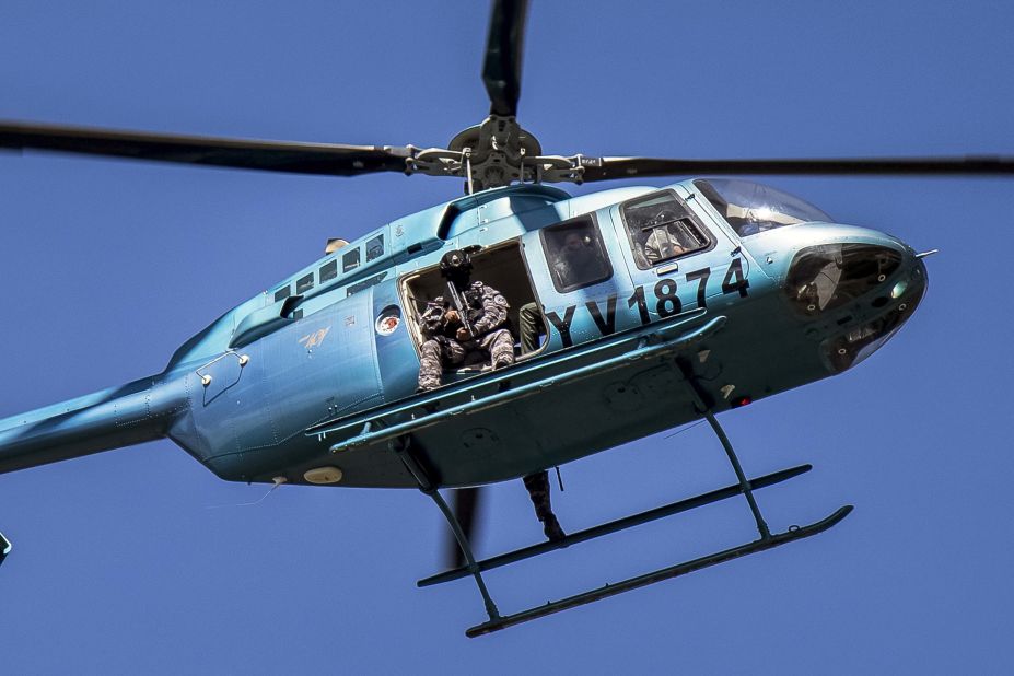 Members of the Venezuelan armed forces fly over Valencia in a helicopter while citizens demonstrate in support of a group that staged a paramilitary uprising at the Paramacay military base on August 6.