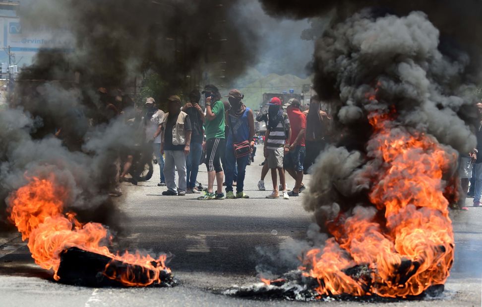 Anti-government activists stand near a flaming barricade in Valencia on August 6.