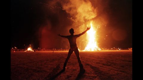 A "Burning Man" participant holds up his arms as the wooden man effigy is burned at the conclusion of an earlier "Burning Man Festival" in Nevada's Black Rock Desert. More than 15,000 people congregated at this man-made town in the desert to celebrate radical, creative self-expression. 