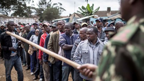 A police officer directs voters toward the back of the line at a Nairobi polling station.