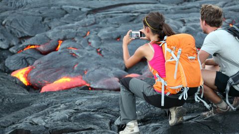 Hawaii lava tourist. Tourists taking photo of flowing lava from Kilauea volcano around Hawaii volcanoes national park, USA.; Shutterstock ID 123043051