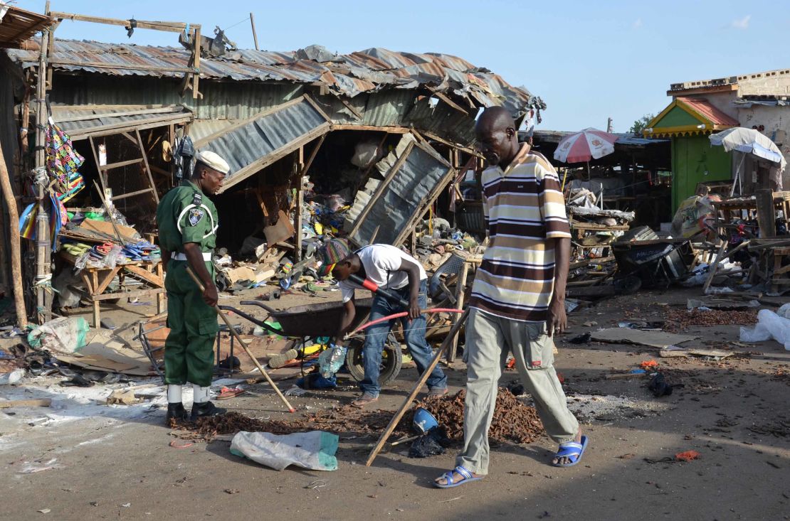 A man walks past the scene of a bombing in Maiduguri. At least 20 people were killed when a young female suicide bomber detonated her explosives at a bus station near a fish market on June 22, 2015.