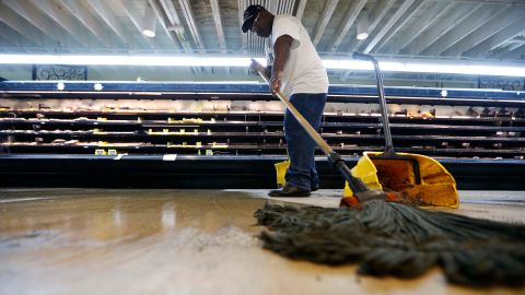 Randy Davis, manager at the Circle Food Store, mops the floor after the store flooded during Saturday's torrential rains in New Orleans