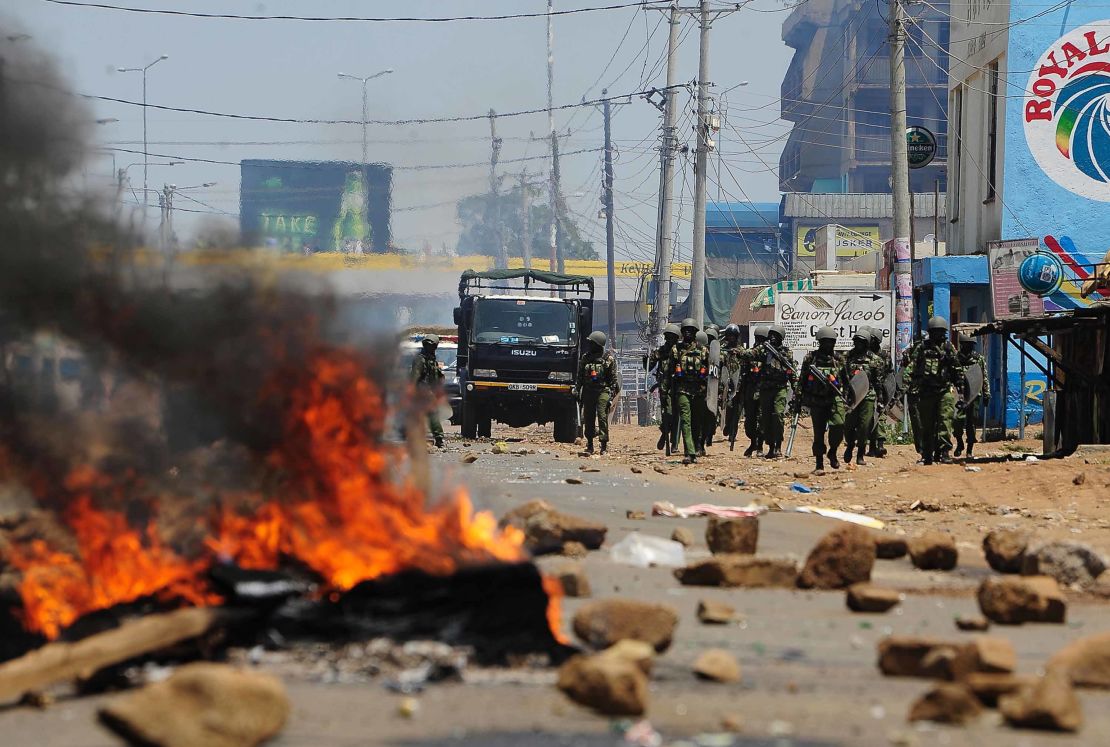Kenyan security personnel walk towards burning tire barricades on a road in Kisumu after clashes between opposition support and police on Wednesday. 