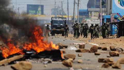 Kenyan security personnel walk towards burning barricades on a road in Kisumu on Wednesday.