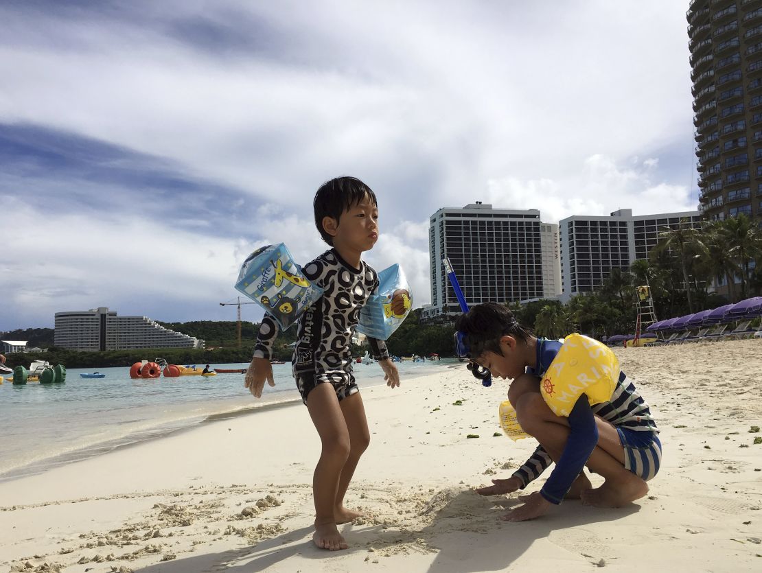 Children play in the sand in Tumon, Guam, on Thursday, August 10.