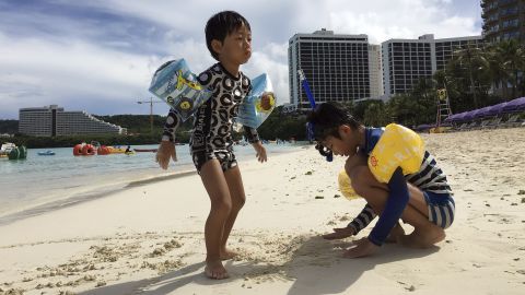 Children play in the sand in Tumon, Guam, on Thursday, August 10.