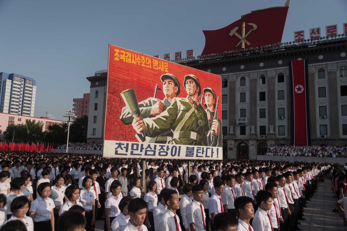 People in Pyongyang, North Korea, attend a rally Wednesday, August 9, in the capital's Kim Il Sung Square. The rally showed support for the North Korean government and its bellicose stance against the United States. The sign here reads "protect our nation to the death" and "hearts of 10 million people are burning."