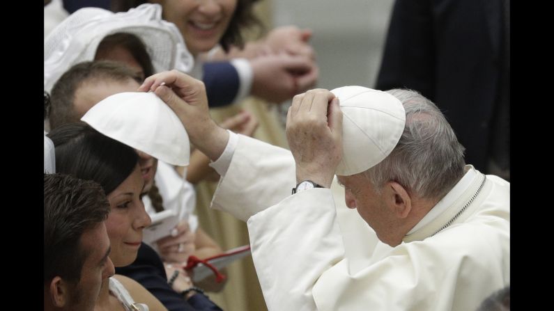 Pope Francis exchanges skullcaps with a woman during his weekly address at the Vatican on Wednesday, August 9. 