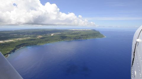 Guam's green flora and Andersen Air Force base can be seen from above.