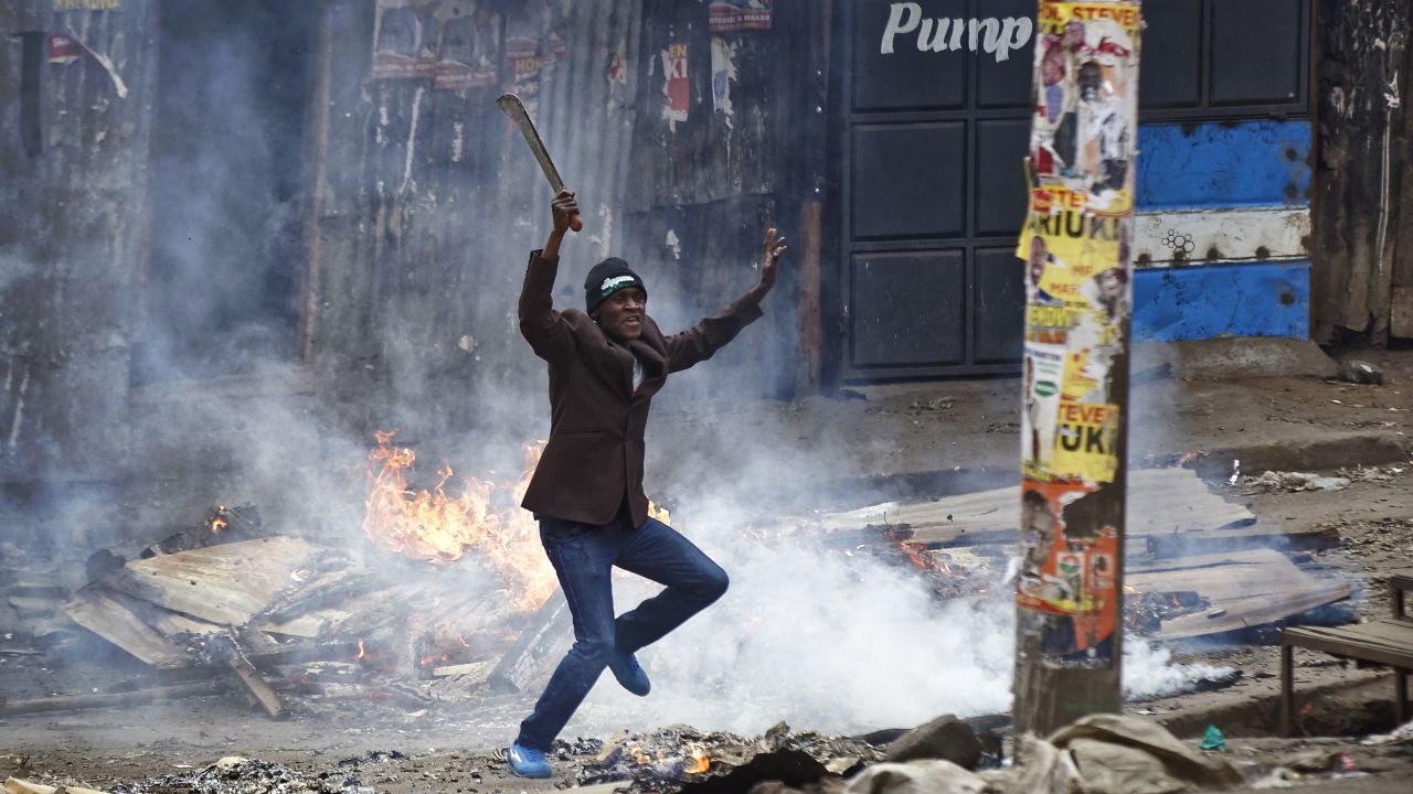A man brandishing a machete challenges police next to a burning barricade during clashes between police and protesters in the Mathare slum of Nairobi.