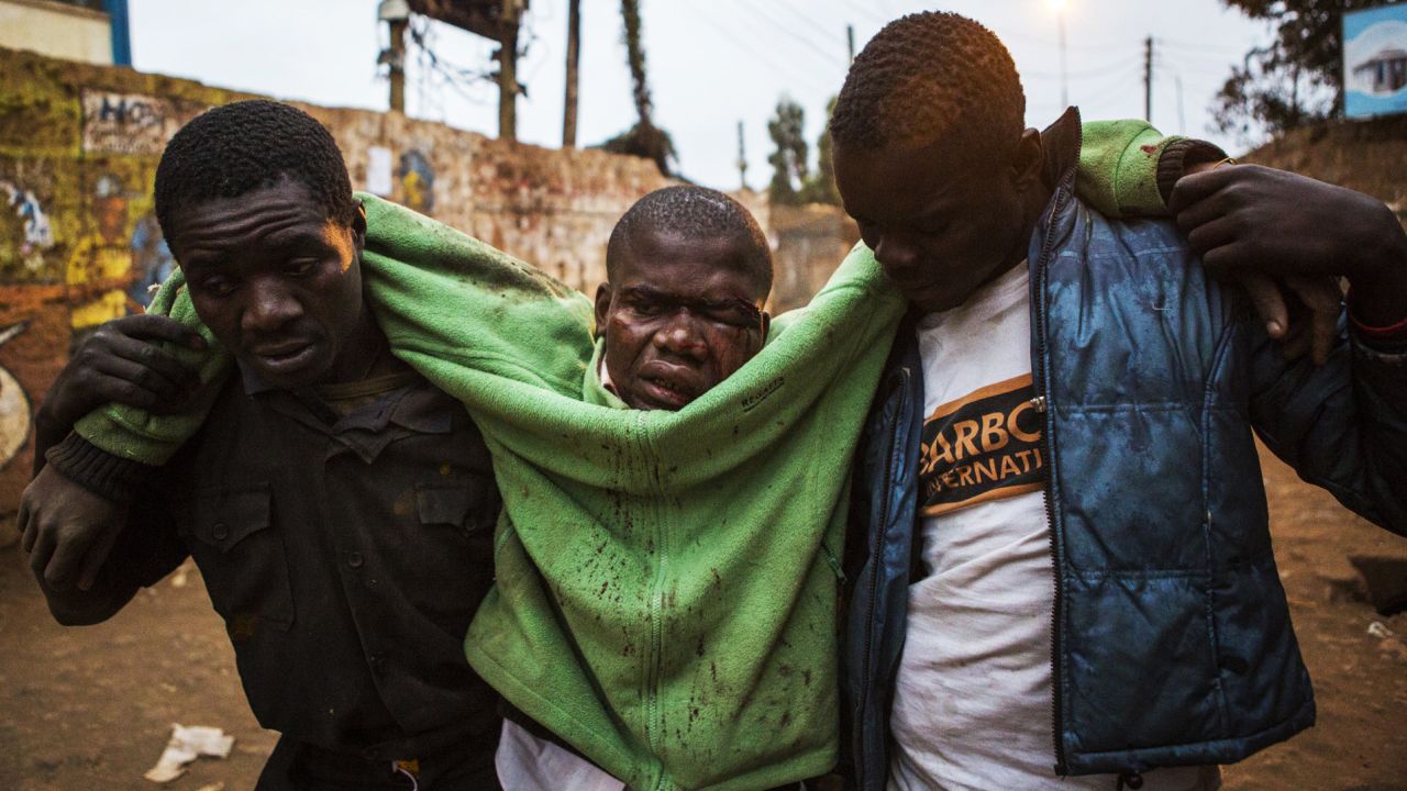 An injured man is carried in the Kibera slum of Nairobi.