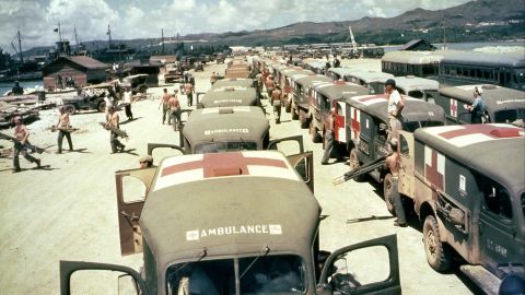 Military ambulances are lined up on shore at Guam, awaiting the arrival of the USS Solace with casualties from Okinawa, in June 1945. 