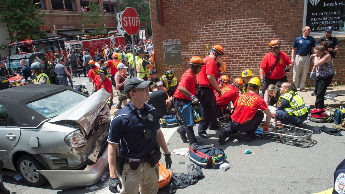 A woman receives first aid after a speeding car slammed into this silver convertible as it navigated through a crowd of counterprotesters. 