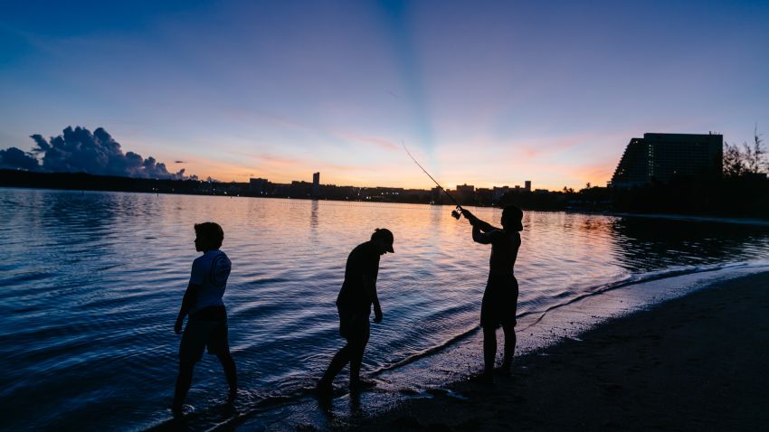 As dawn breaks, Leonard Calvo, left, fishes with his brothers at Ypao Beach Park.
