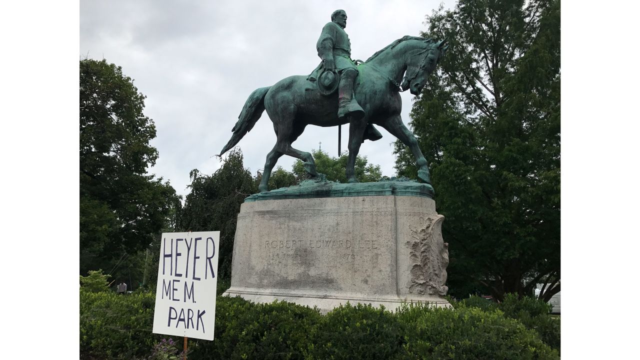 A sign remembering Heather Heyer sits in front of a statue of Robert E. Lee in Emancipation Park.