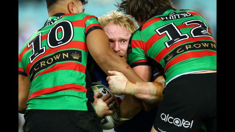 James Graham is tackled by two South Sydney Rabbitohs during a National Rugby League match in Sydney on Thursday, August 10.