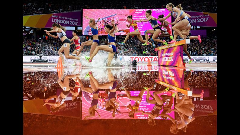 Athletes jump over a water obstacle during a steeplechase race at the World Championships on Wednesday, August 9.