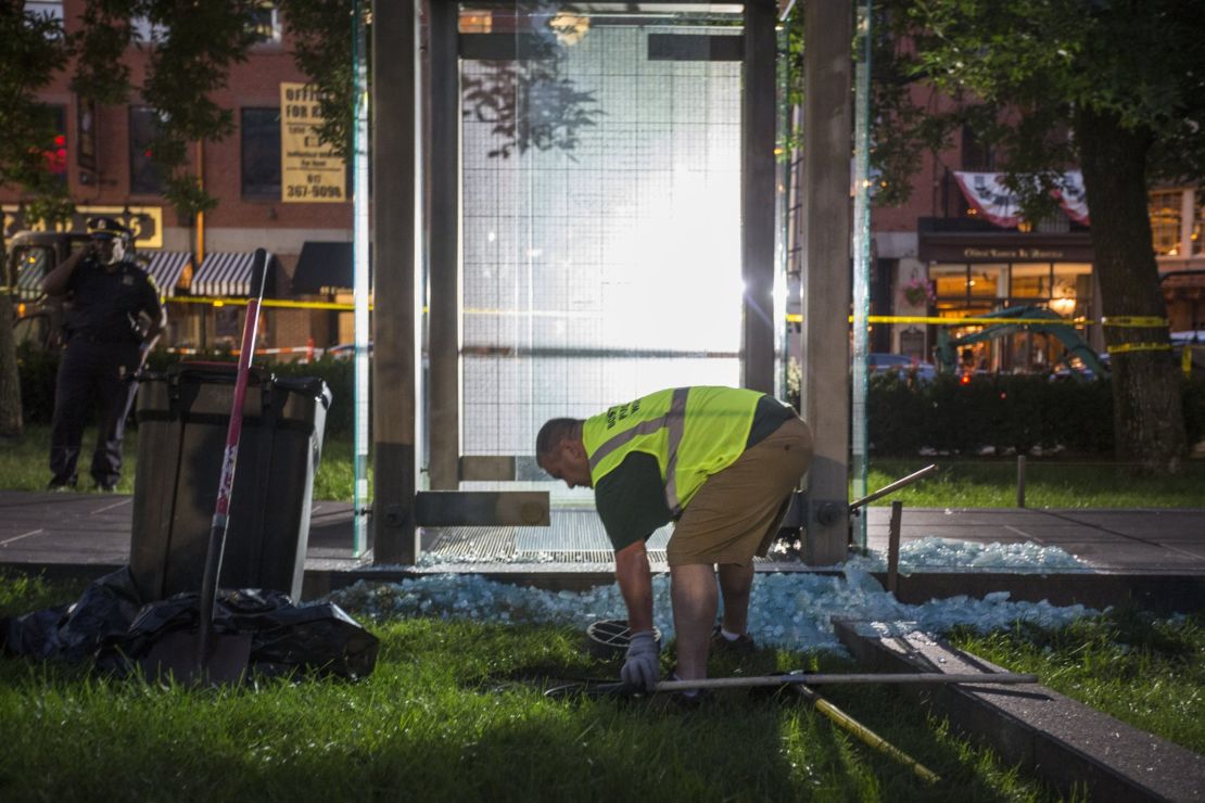 A worker cleans up broken glass at the New England Holocaust Memorial that was vandalized Monday.