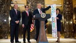 Flanked by (L to R) Director of the National Economic Council Gary Cohn, Treasury Secretary Steve Mnuchin and Transportation Secretary Elaine Chao, President Donald Trump holds up a Federal decision permitting-process flowchart for federally funded highway projects in the United States' while speaking following a meeting on infrastructure at Trump Tower, August 15, 2017 in New York City.  He fielded questions from reporters about his comments on the events in Charlottesville, Virginia and white supremacists. 